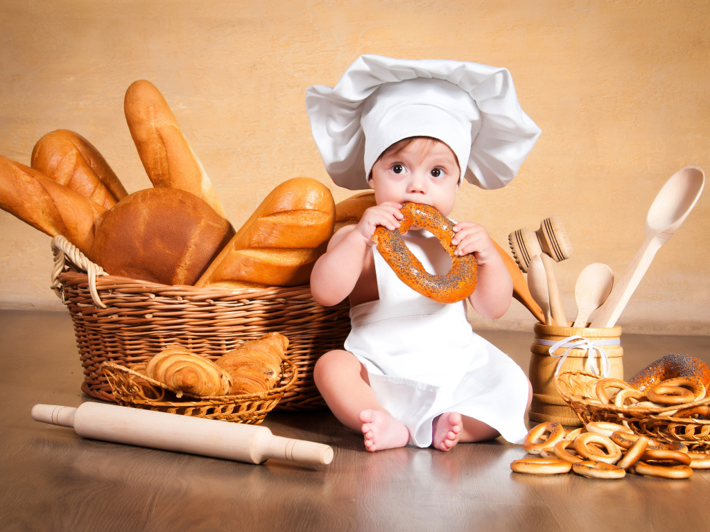 Маленький мальчик с хлебобулочными изделиями на столе 