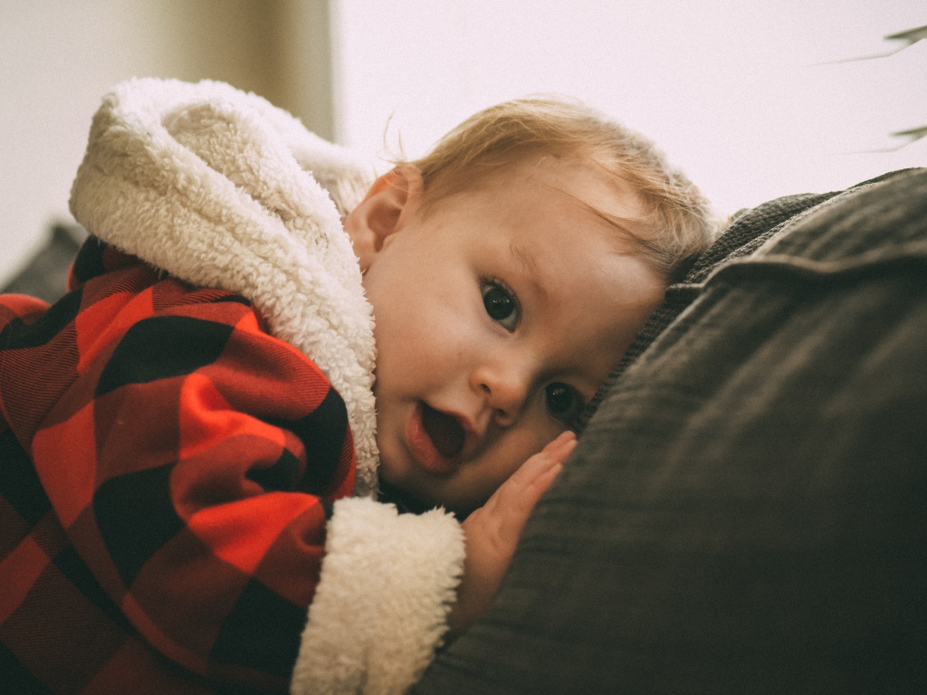 Маленький забавный малыш лежит на диване