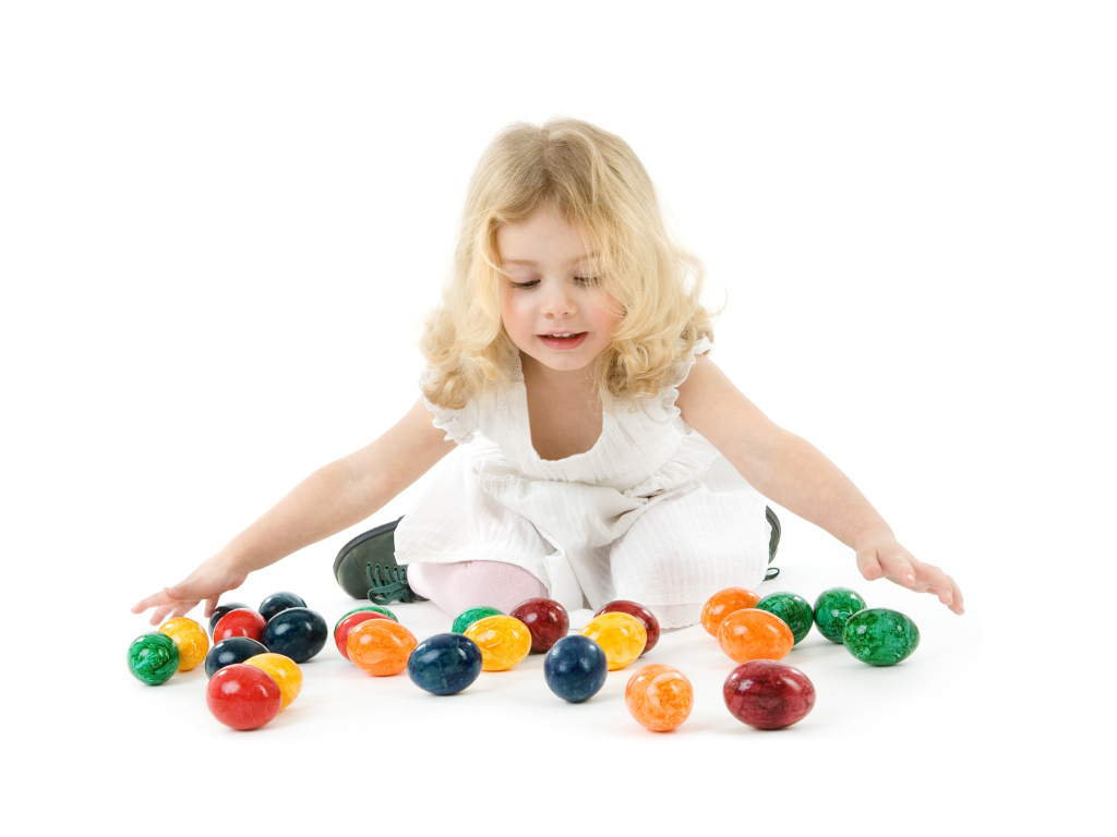 Маленькая девочка блондинка с крашеными яйцами на белом фоне