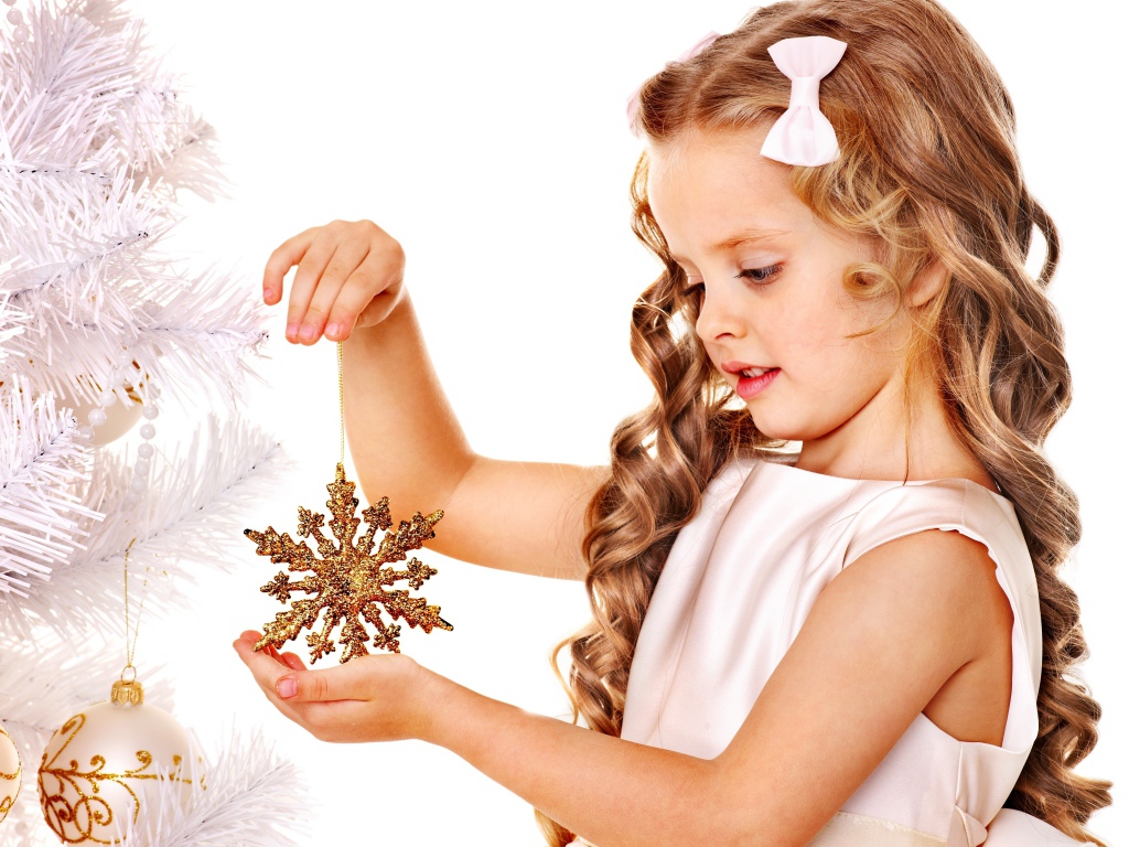 Маленькая девочка держит елочную игрушку снежинку в руке