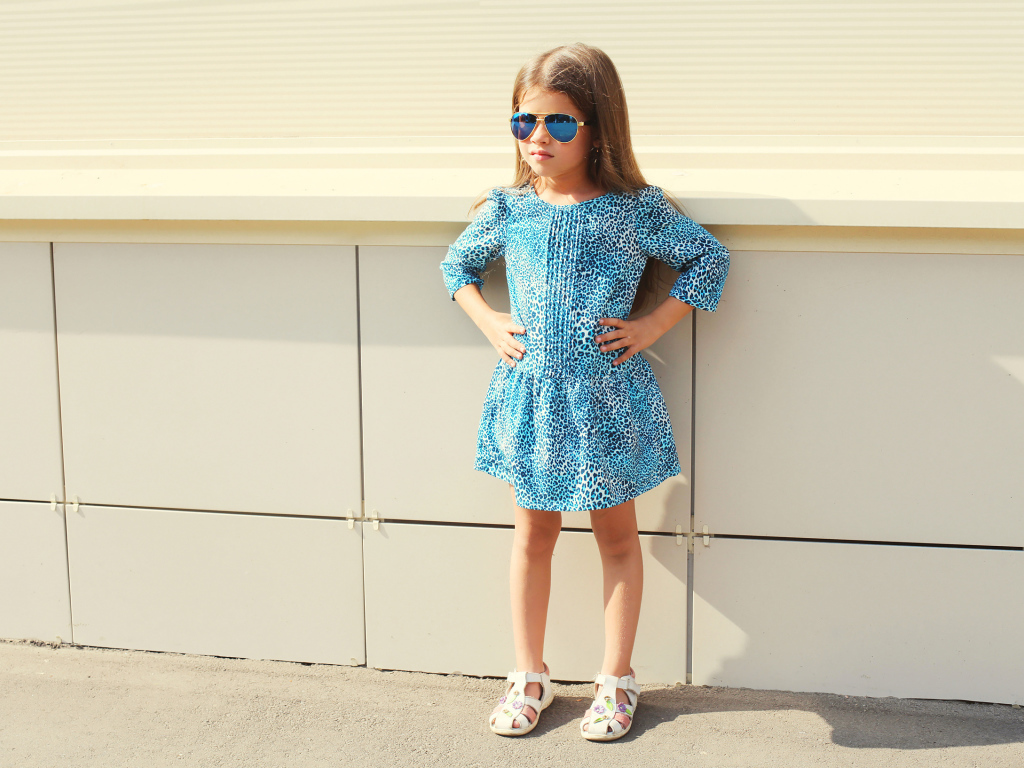 Маленькая девочка в красивом платье у стены