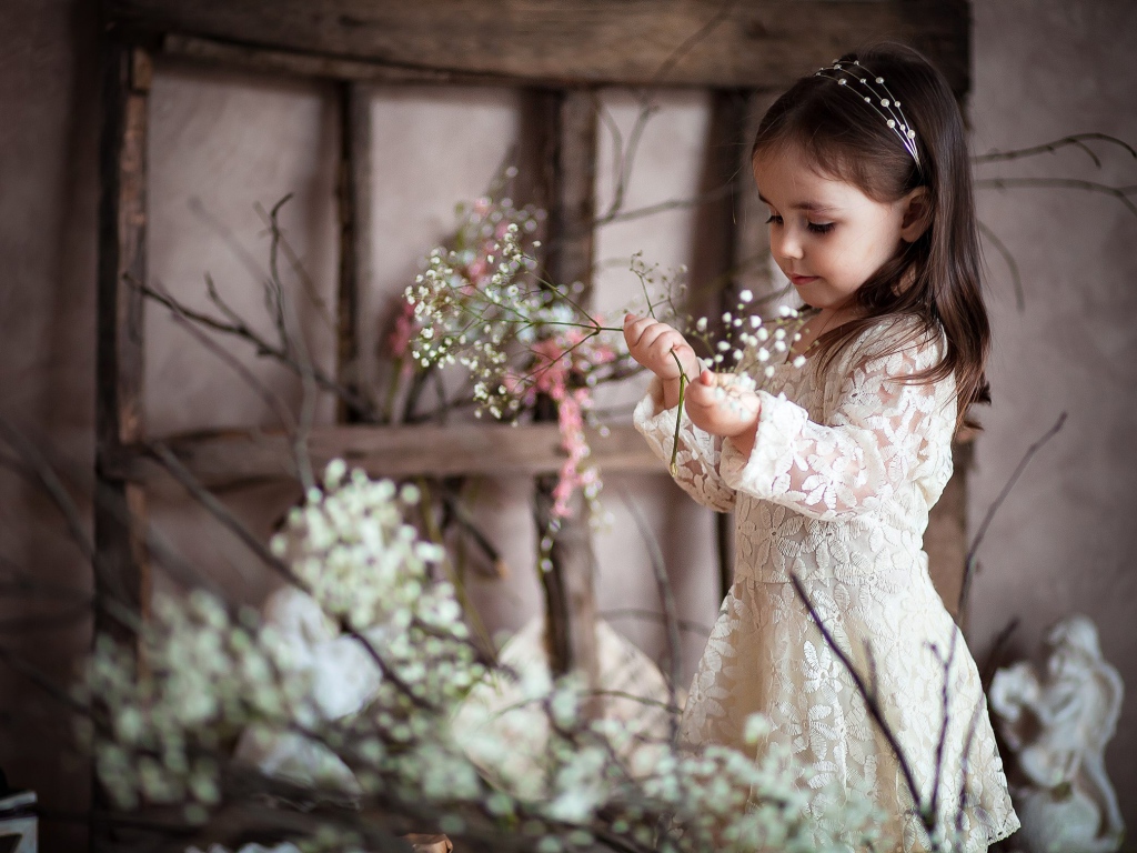 Маленькая девочка в красивом платье с белыми цветами в руке