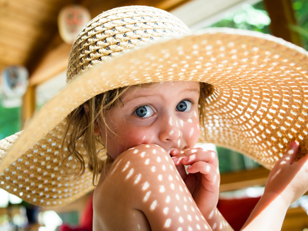 Маленькая девочка в большой соломенной шляпе летом