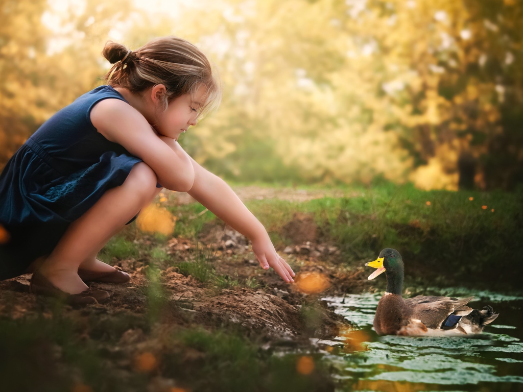 Маленькая девочка играет с уточкой в воде