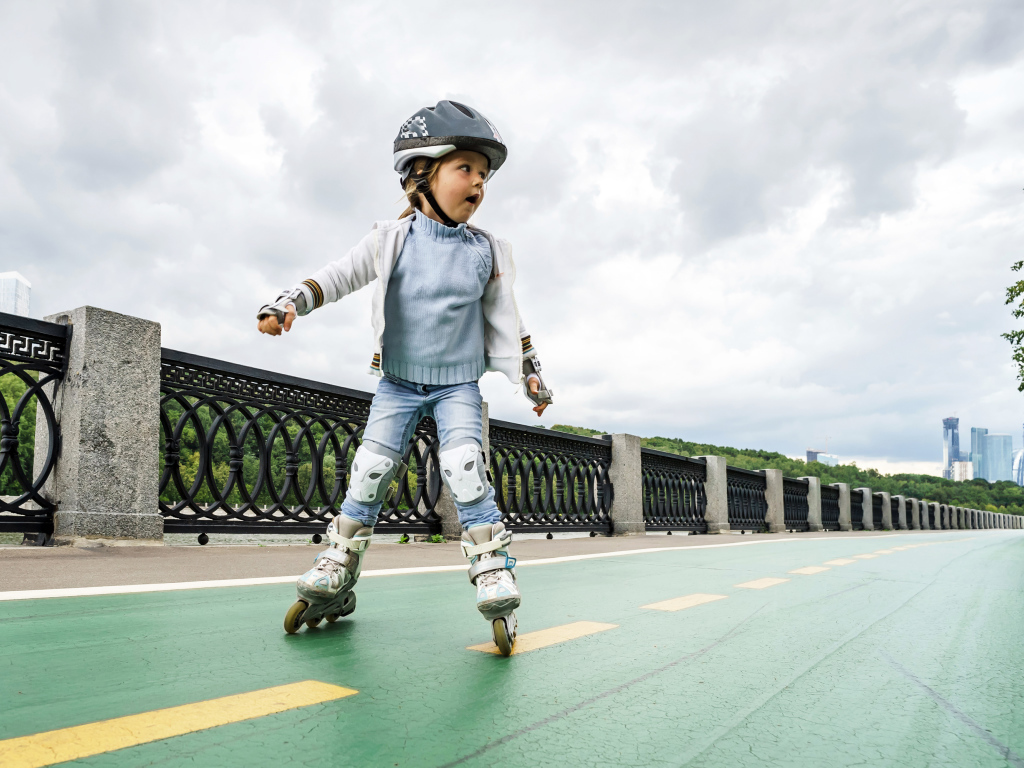 Маленькая девочка катается по мосту на роликах