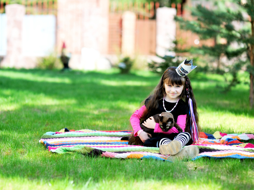 Маленькая девочка с котом сидит на зеленой траве