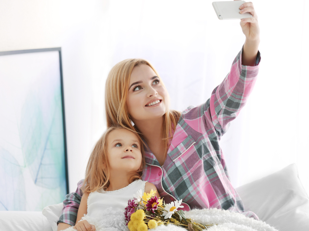 Маленькая девочка с мамой делают фото на смартфон