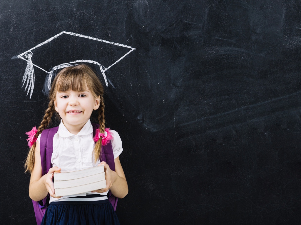 Маленькая школьница с книгами у доски 