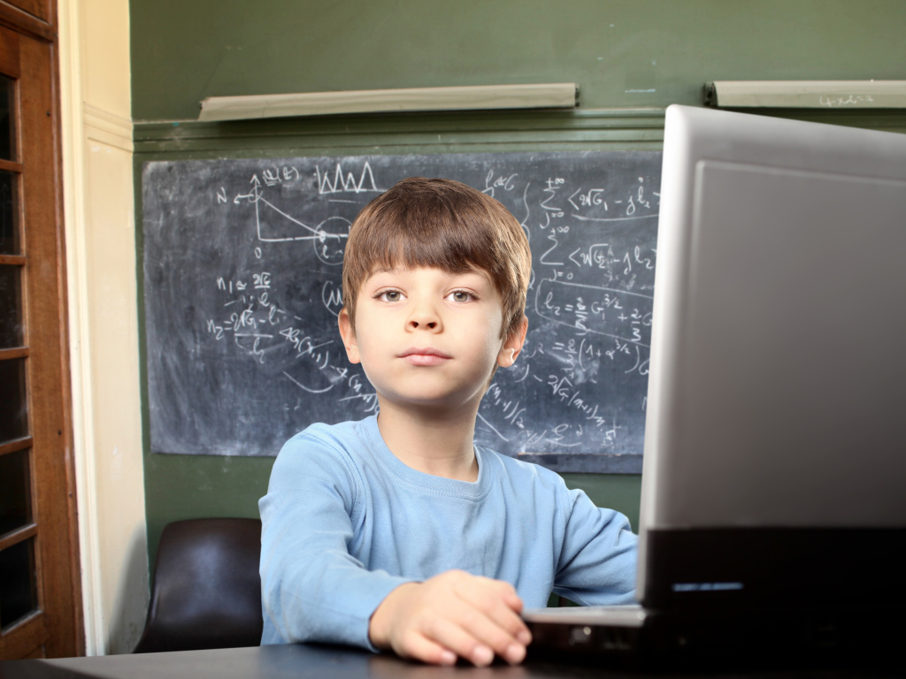 Мальчик школьник делает уроки за ноутбуком