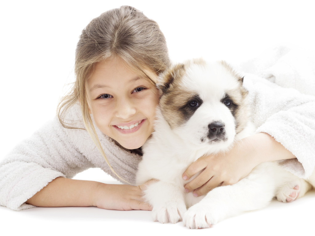 Улыбающаяся девочка лежит с щенком алабая