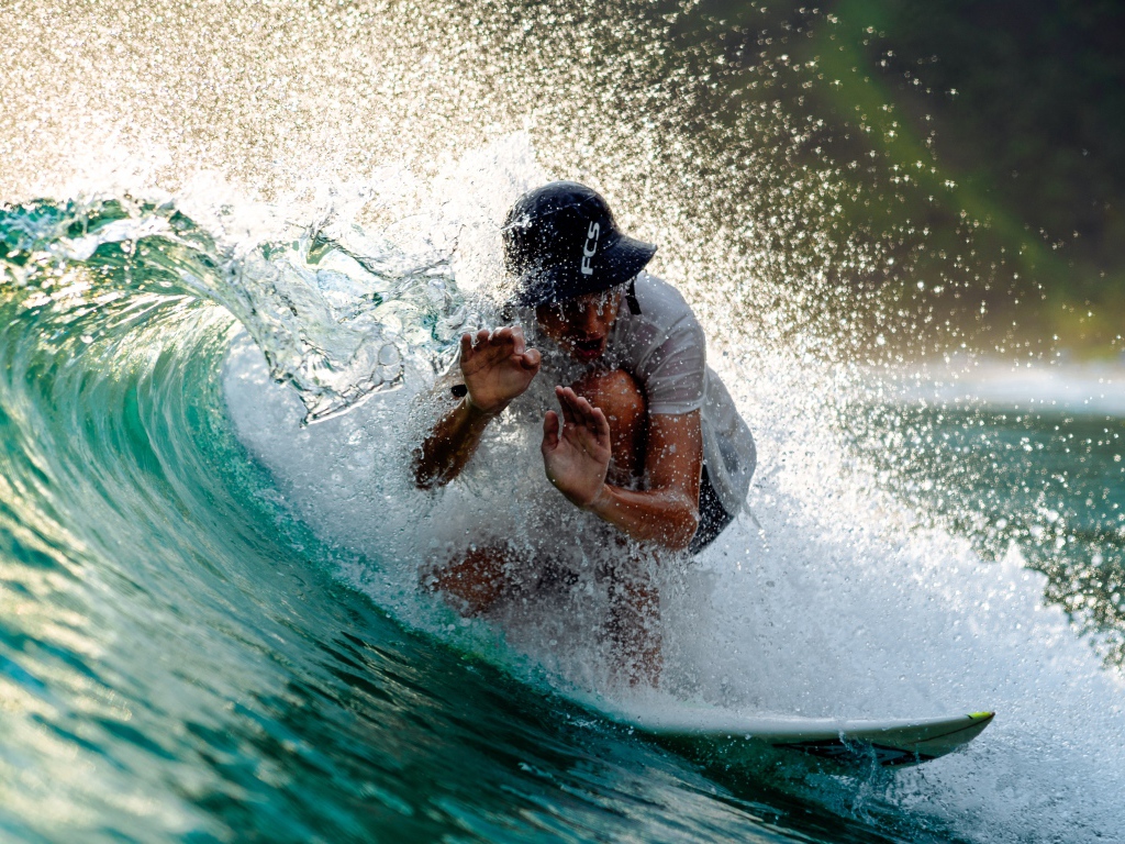 Парень серфингист ловит голубую морскую волну