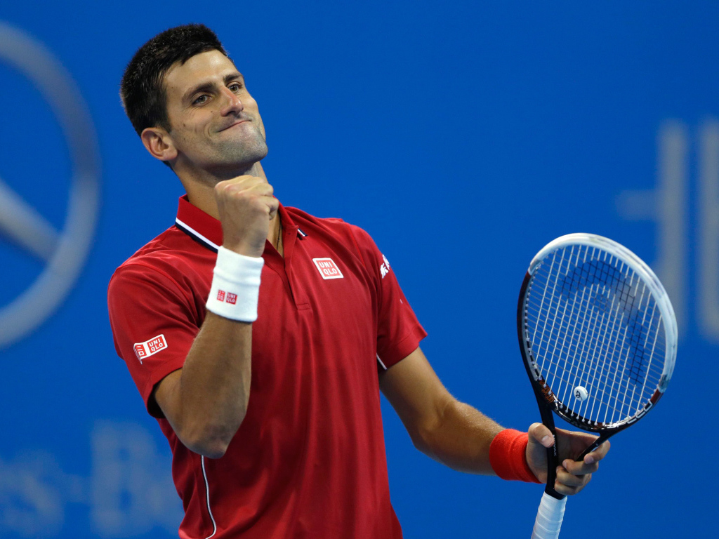 Теннисист Новак Джокович с ракеткой радуется на корте