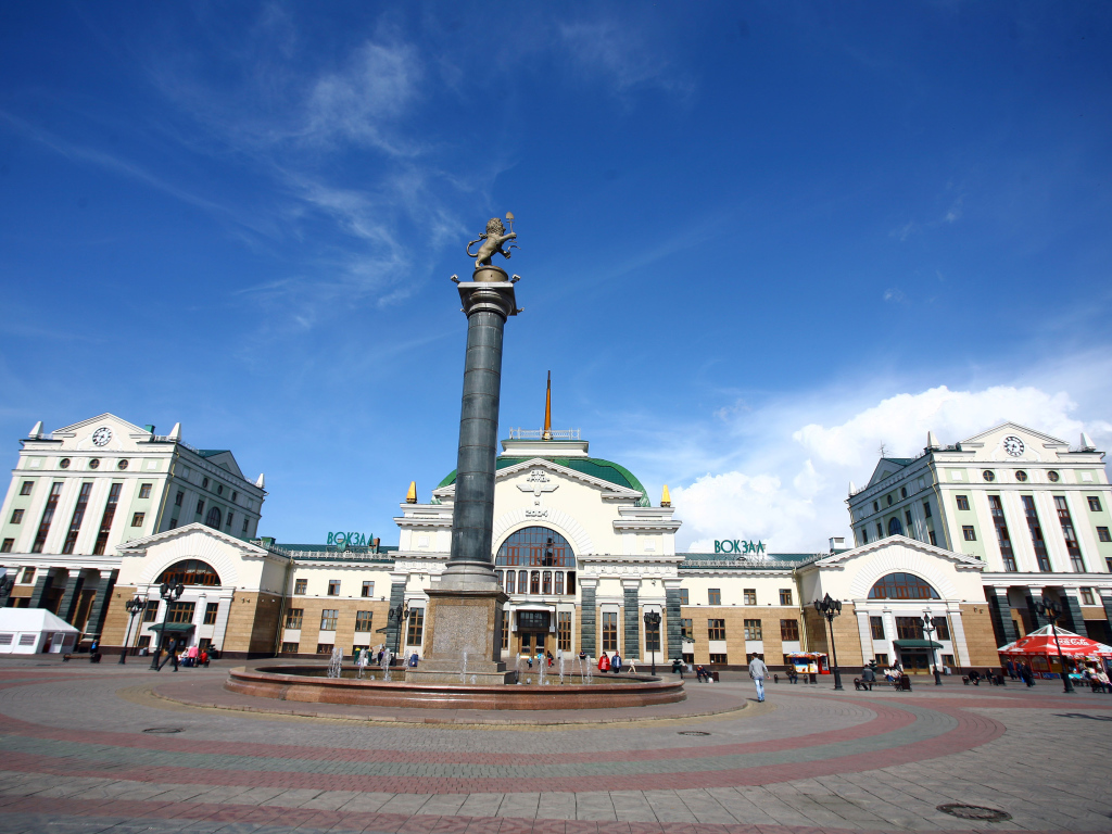 Памятник у здания железнодорожного вокзала под красивым голубым небом, Красноярск. Россия