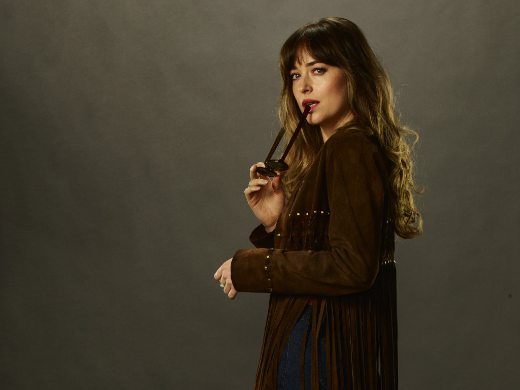 Актриса Дакота Джонсон с очками в руке на сером фоне