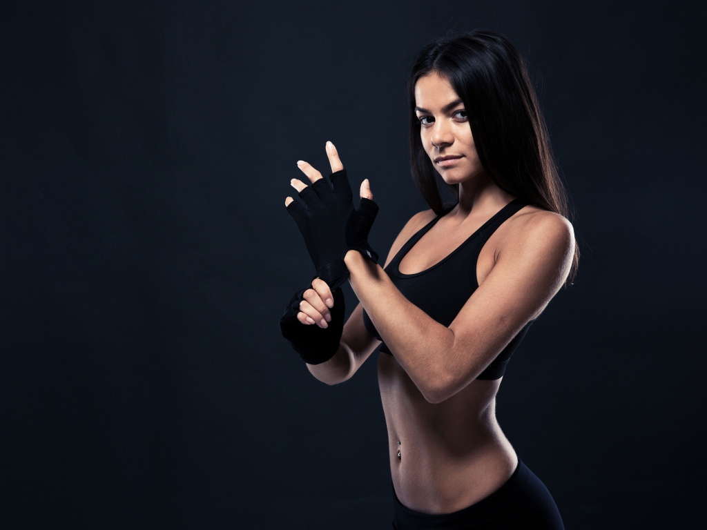 Красивая спортивная девушка в перчатках на сером фоне