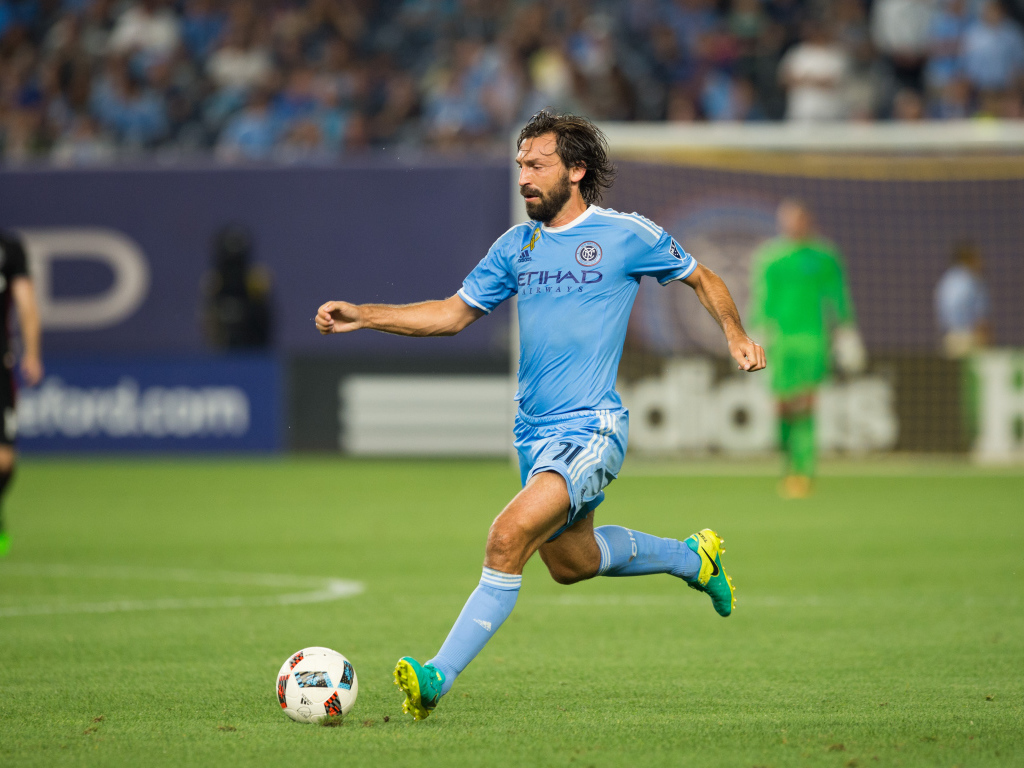 Итальянский футболист Андреа Пирло отбивает мяч на футбольном поле