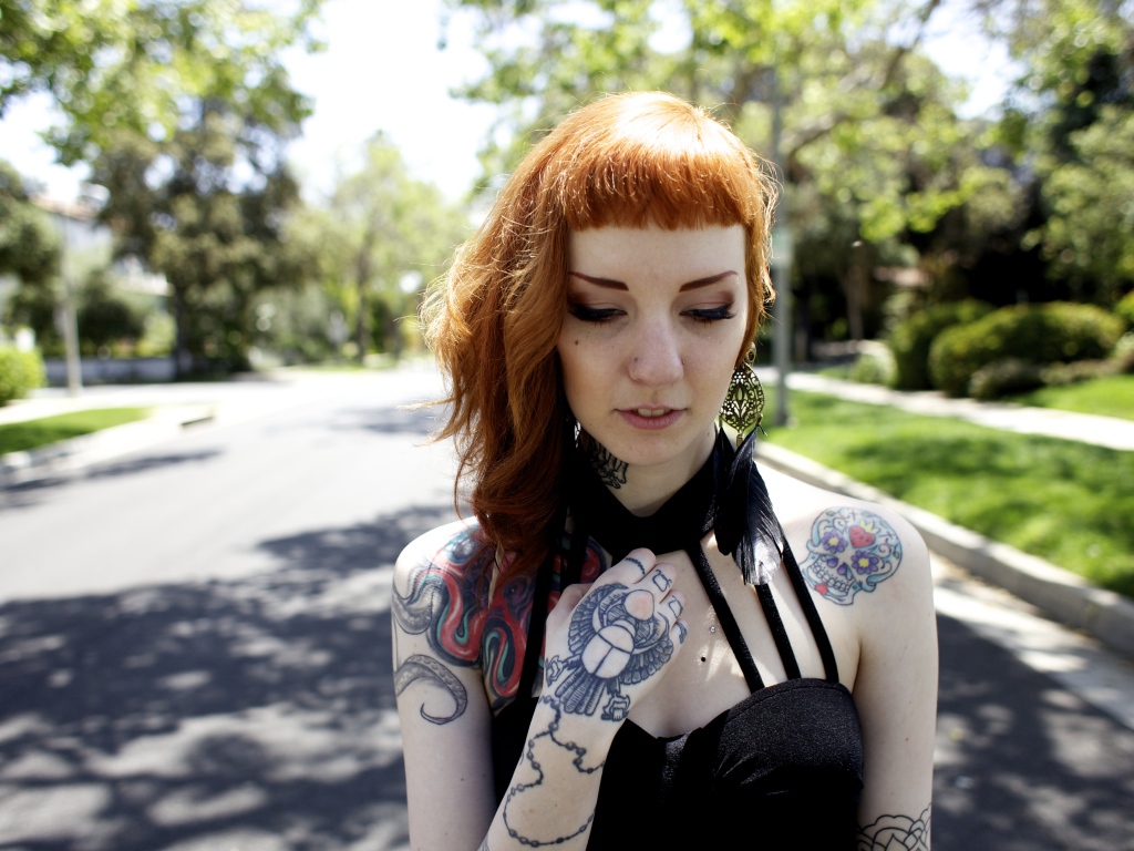 Рыжеволосая девушка неформалка с татуировками на теле