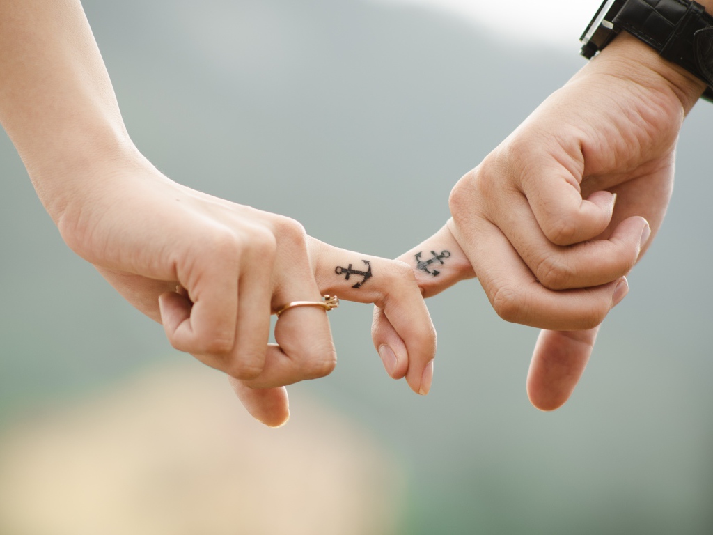 Tattoo with anchor on the fingers of a couple in love