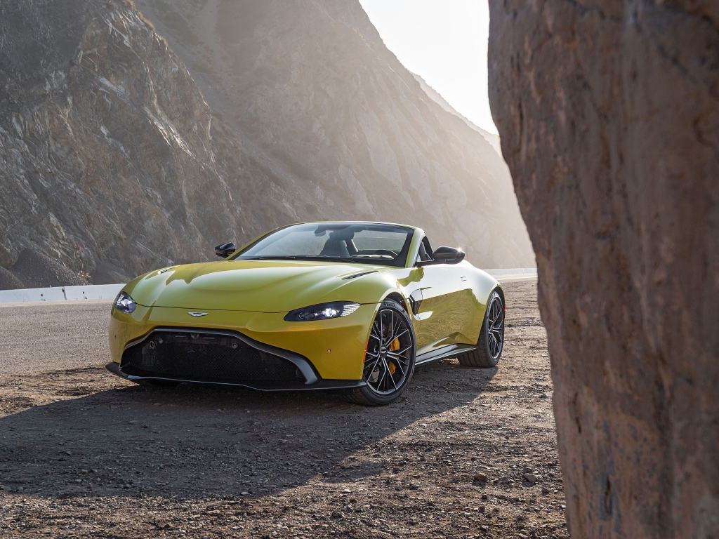 Желтый автомобиль  Aston Martin Vantage Roadster, 2021 года в горах 