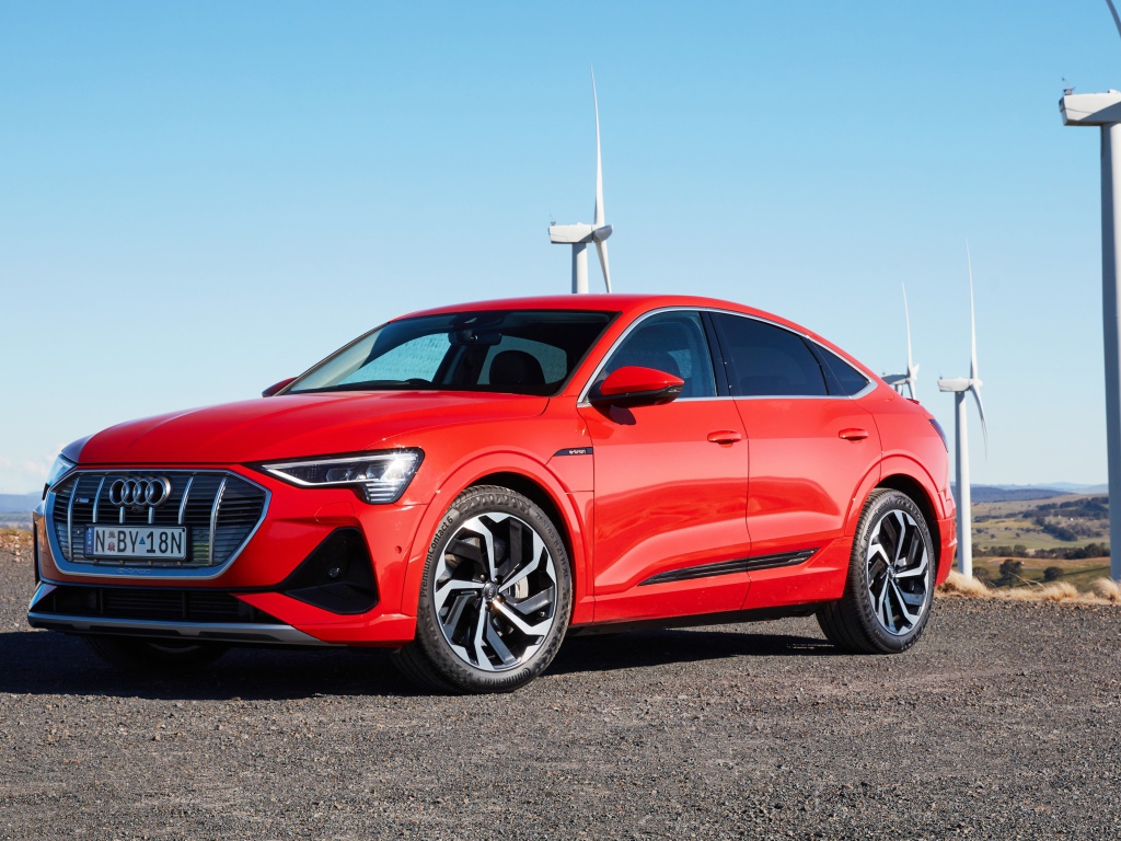 Красный автомобиль Audi E-Tron 50 Quattro Sportback S Line 2020 на фоне ветряных турбин