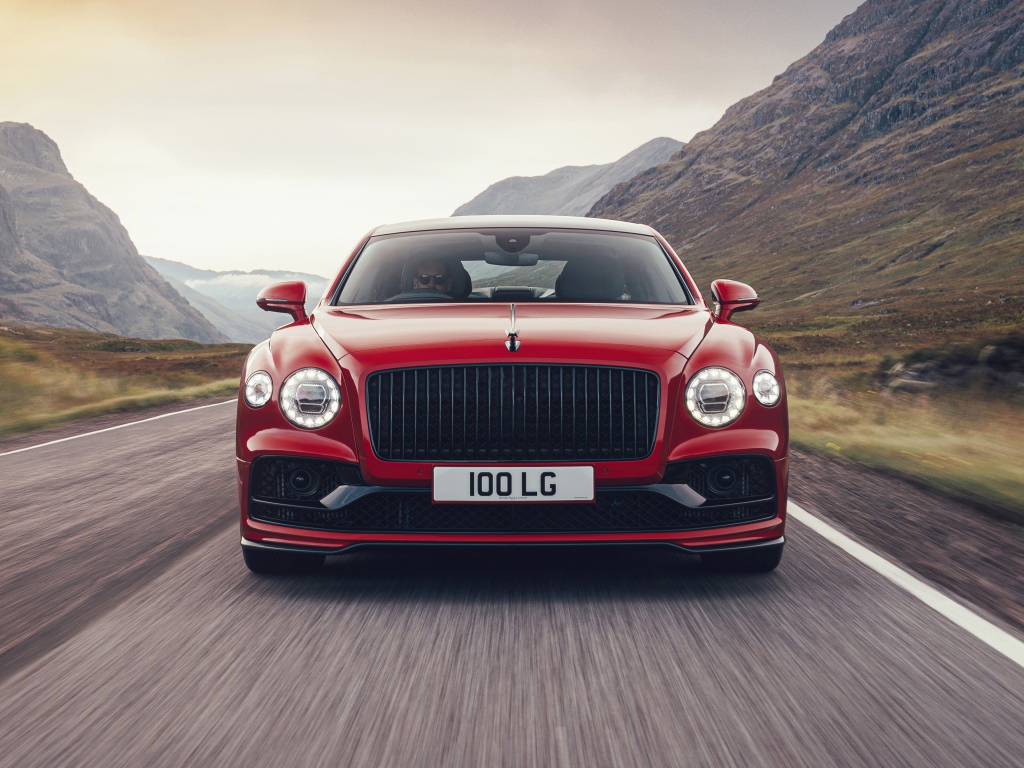 Красный автомобиль Bentley Flying Spur V8 2020 года на дороге в горах 