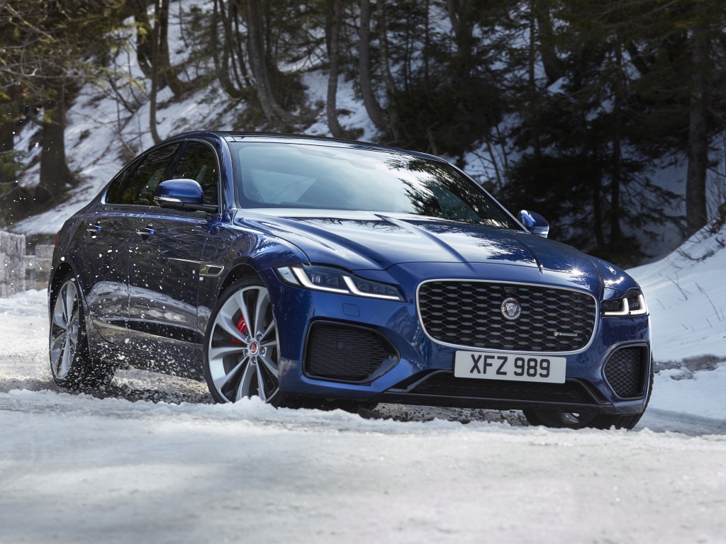 Синий Jaguar XF P300 AWD R-Dynamic 2020 года в заснеженном лесу 
