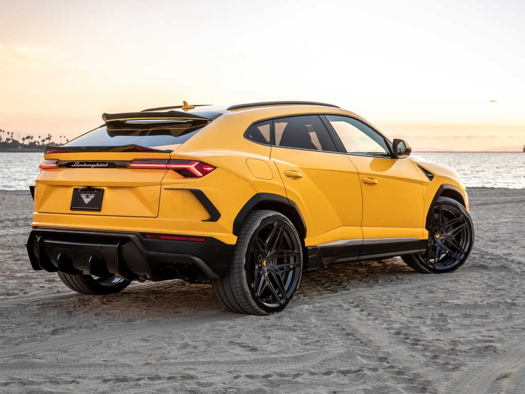 Желтый автомобиль  Lamborghini Urus на песке у моря
