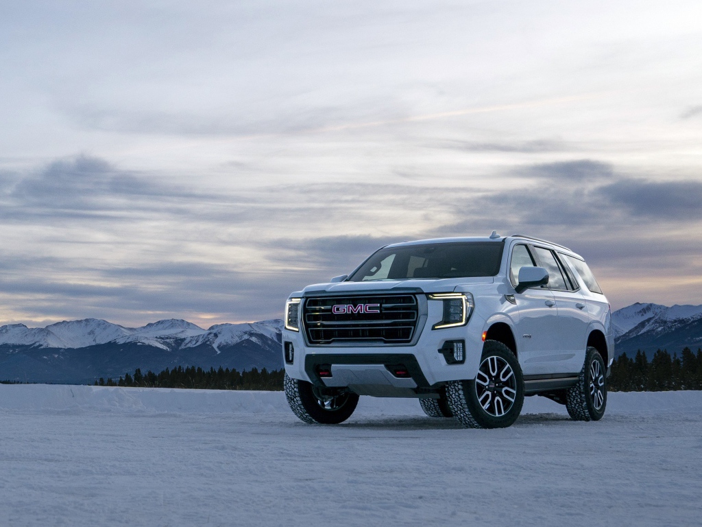 Белый внедорожник  GMC Yukon AT4, 2021 года на фоне заснеженных гор 