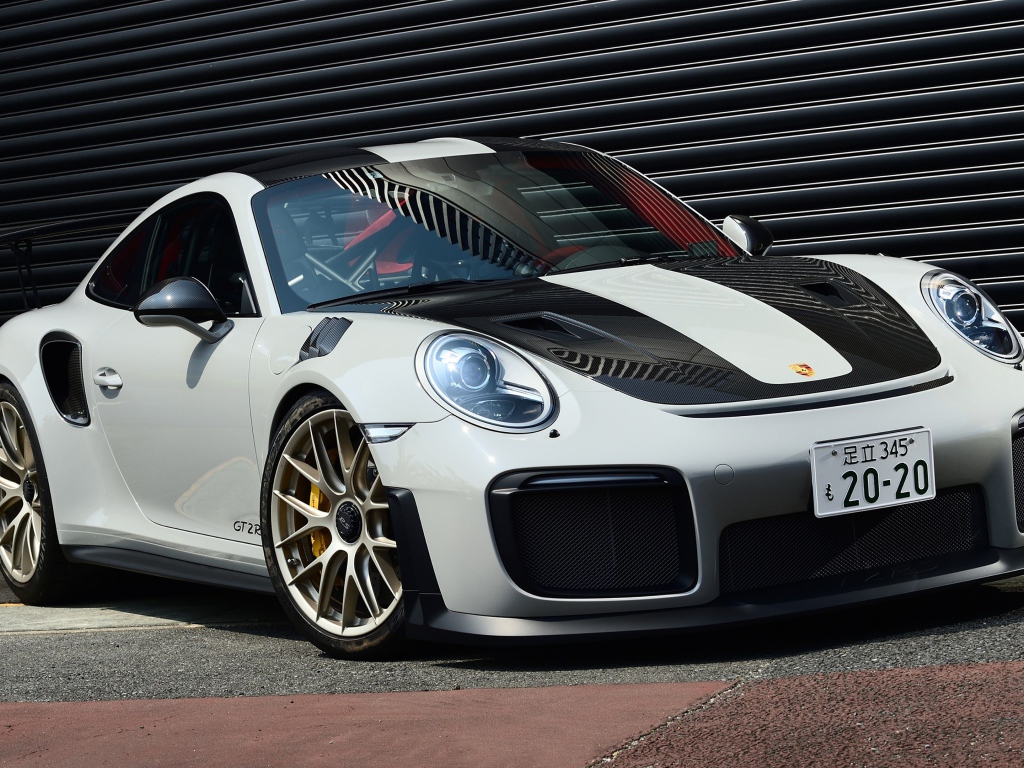 Белый автомобиль Porsche 911 GT2 RS  у черной стены