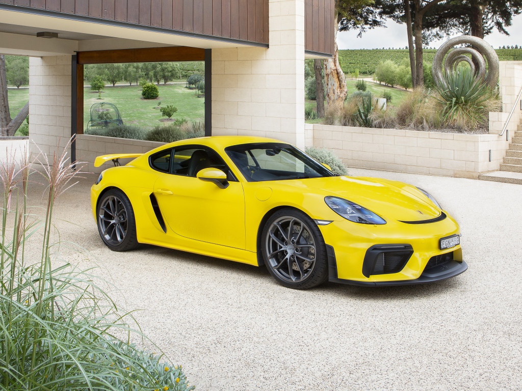 Желтый автомобиль Porsche 718 Cayman GT4, 2020 года у дома