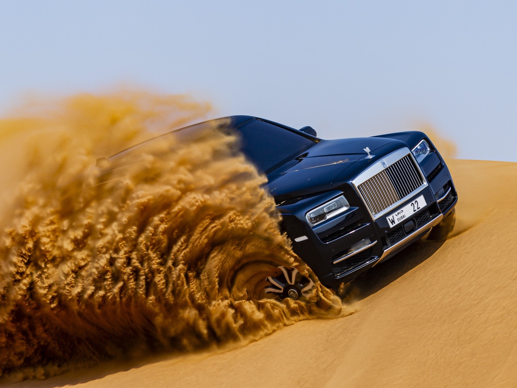 Черный Rolls-Royce Cullinan дрифтует по песку 