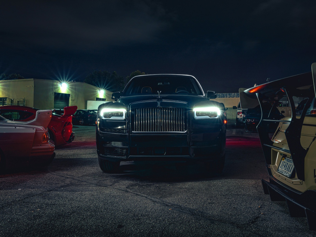 Черный дорогой автомобиль  Rolls-Royce Cullinan, 2020 года с включенными фарами