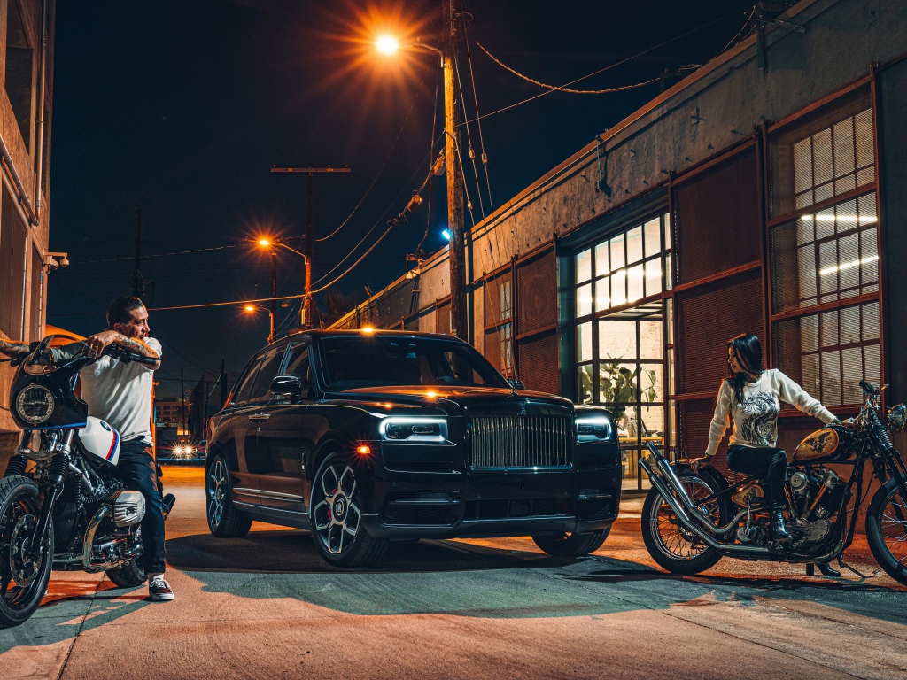 Черный стильный автомобиль Rolls-Royce Cullinan на улице города с байкерами