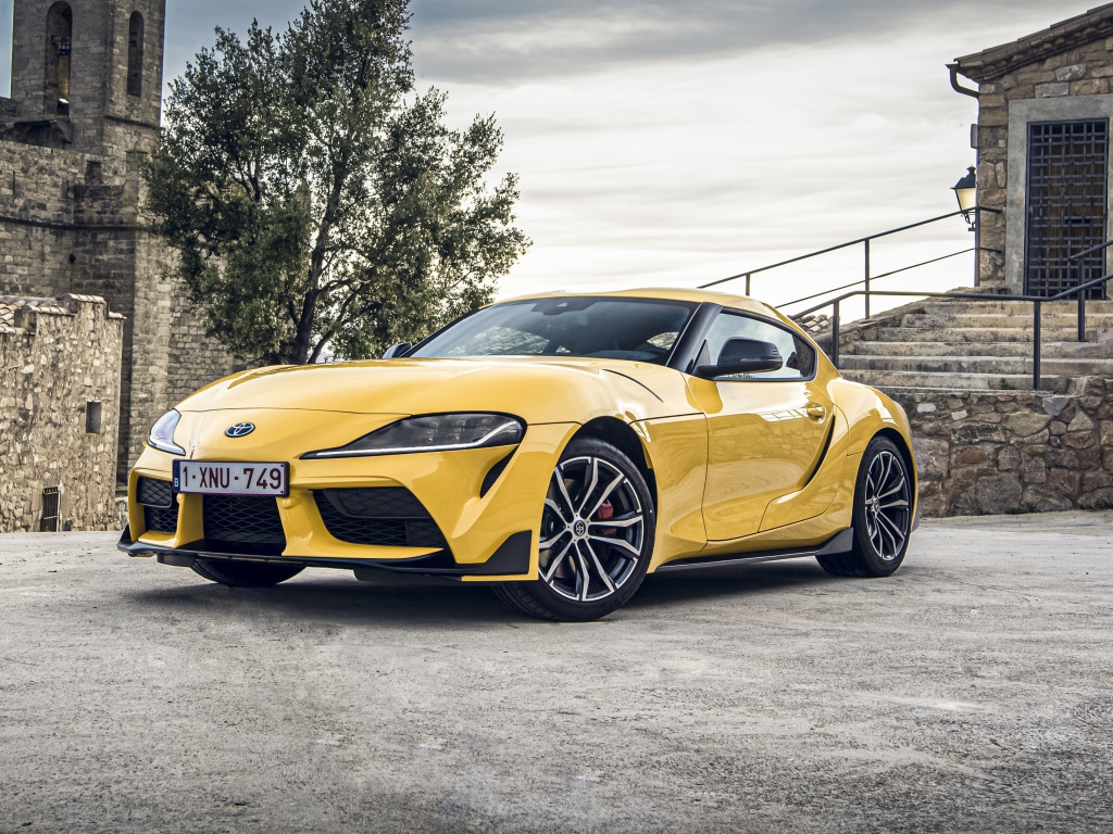 Желтый автомобиль Toyota GR Supra 2, 2020 года у старого здания 