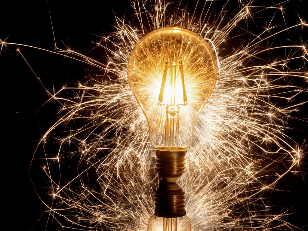 Зажженная лампа на черном фоне с искрами 