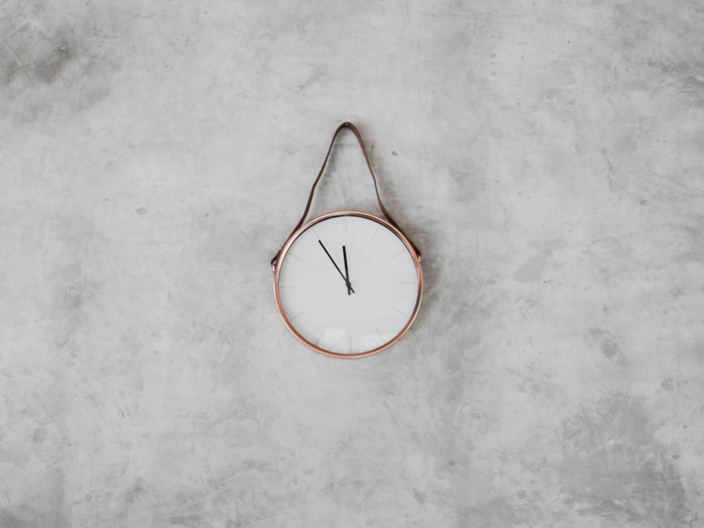 Часы с черными стрелками висят на серой стене 