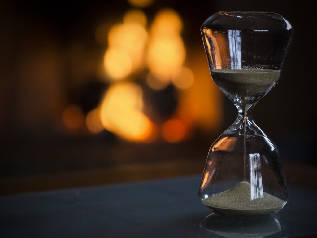 Стеклянные песочные часы на столе 