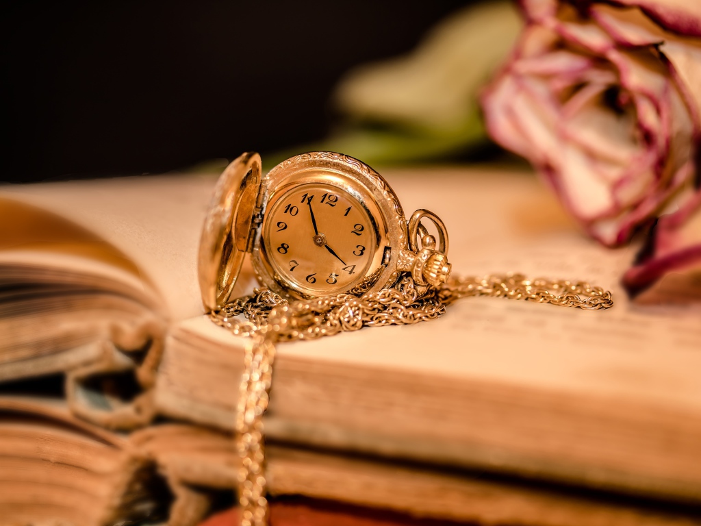 Золотые женские часы на цепочке лежат на книге