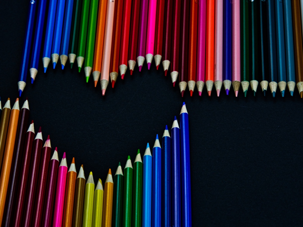 Сердце из разноцветных карандашей на черном фоне