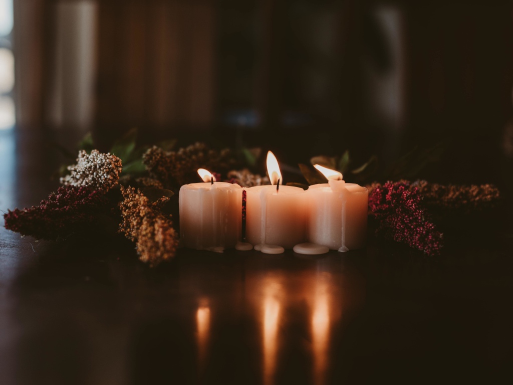 Зажженные свечи с цветами на полу