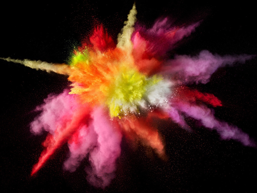 Multicolored explosion of dry paint on a black background