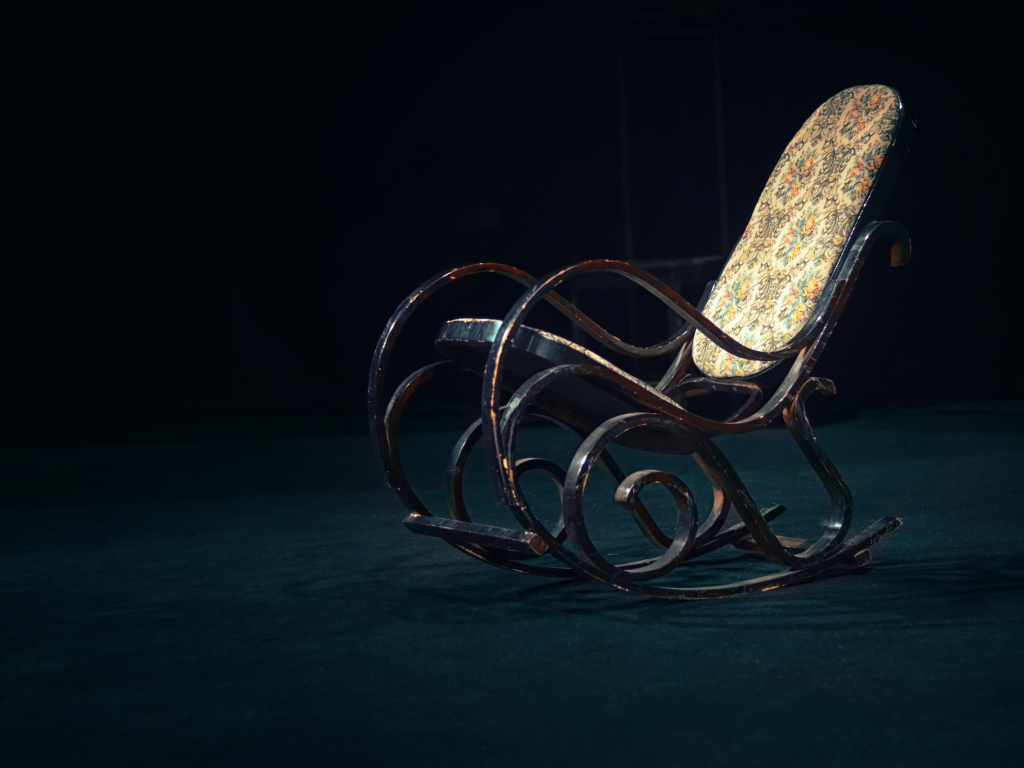 Старое кресло - качалка в темной комнате 