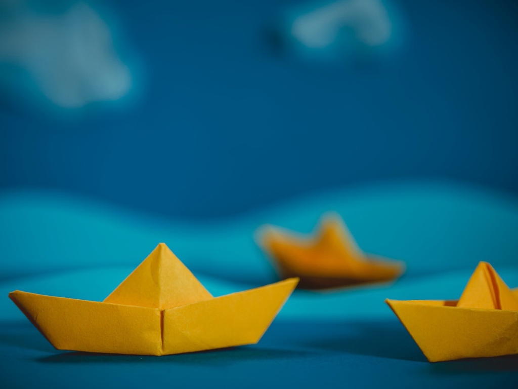 Yellow origami boats on a blue background