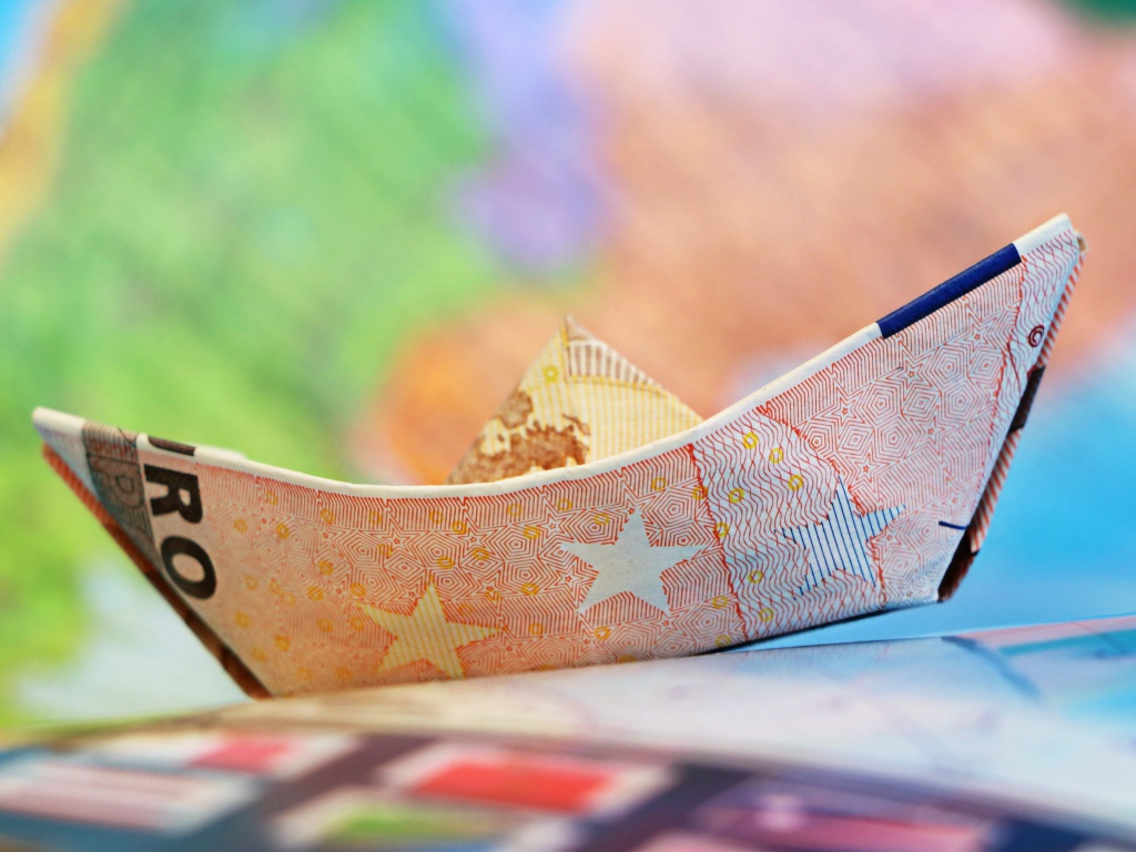 Кораблик из купюры евро на столе 