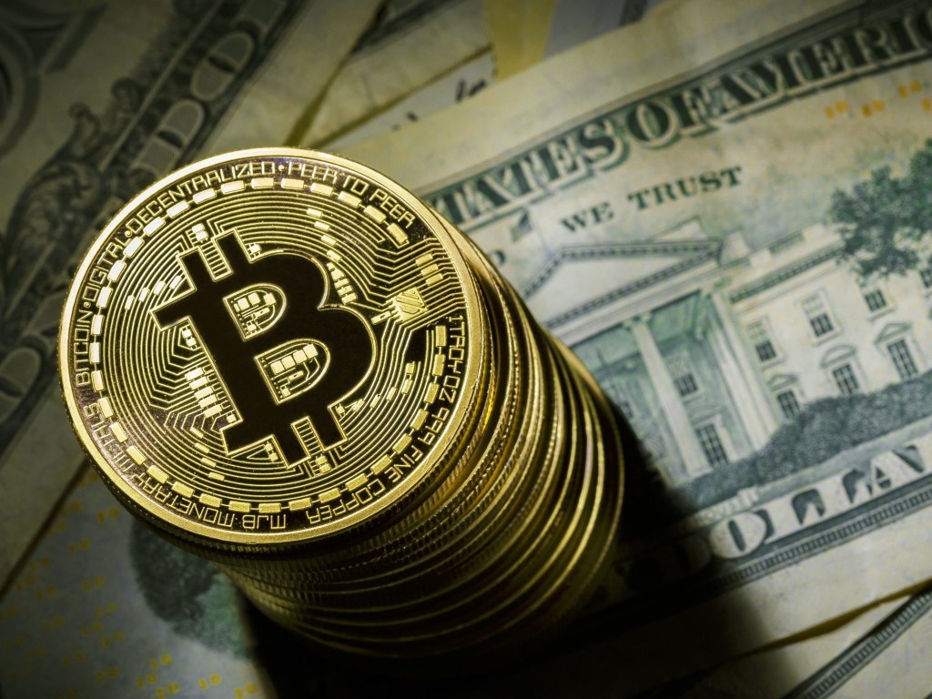 Золотые монеты биткоин лежат на долларах