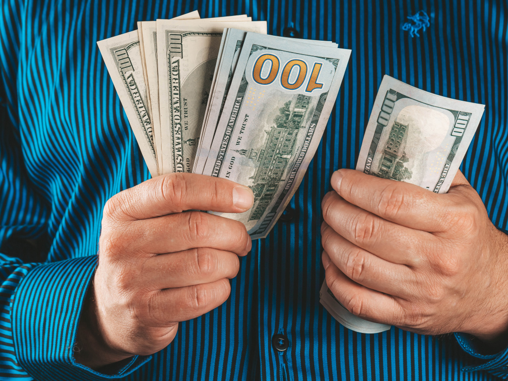 Мужчина считает сто долларовые купюры 