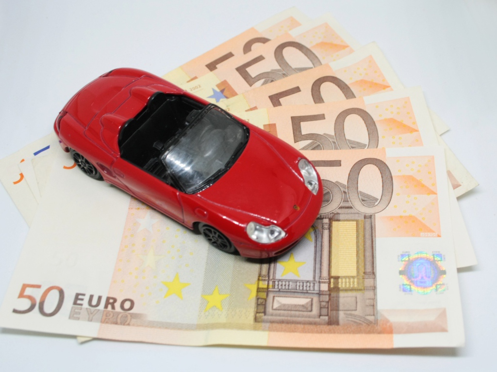 Красная игрушечная машинка с купюрами евро 