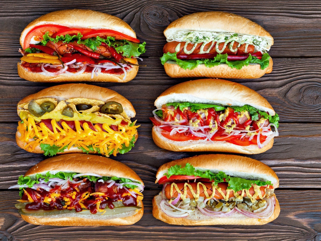 Аппетитные хот доги с разной начинкой на деревянном столе 