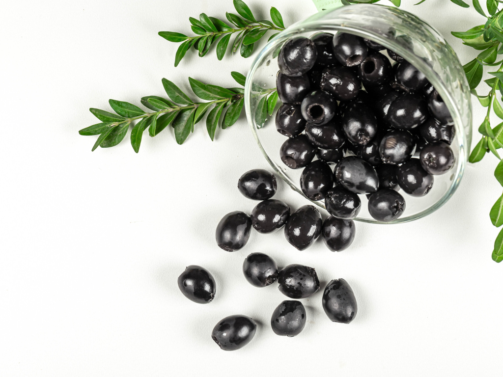 Черные маслины с розмарином на белом фоне