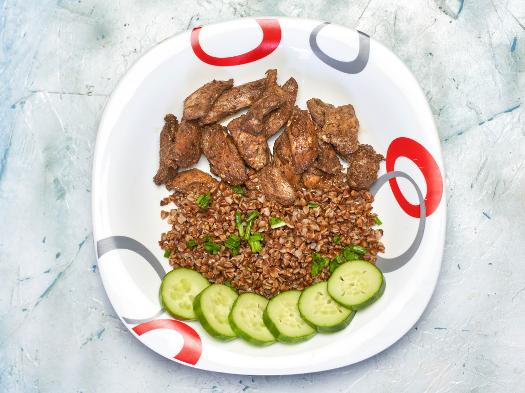 Гречка на тарелке с мясом и огурцами